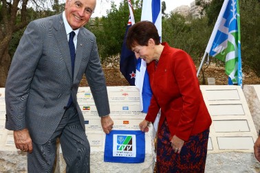 an image of Dame Patsy and Sir David unveil a plaque to mark the planting of an olive tree at the Grove of Nations