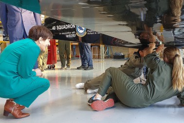 Image of Dame Patsy watching some students fix a plane's undercarriage
