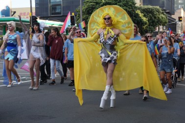 A drag queen in yellow marches in the parade