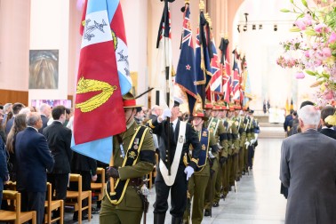 Members of the NZDF march with the Queen's personal flag and the Queen's Colours