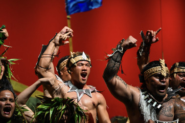 The Cook Islands flag flying behind performers
