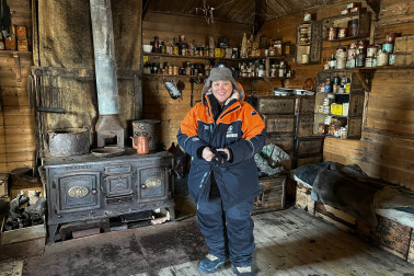 Dame Cindy inside Shackleton's Hut in front of a wrought-iron cooker.