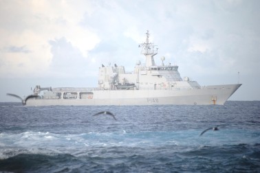 HMNZS OTAGO waits beyond the coral reef surrounding the atoll.