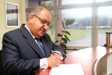 Sir Anand signs the Visitor's Book at Kaikohe East Primary School.