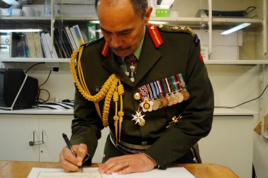 Sir Jerry Mateparae signs the HMNZS Resolution Visitor's Book.