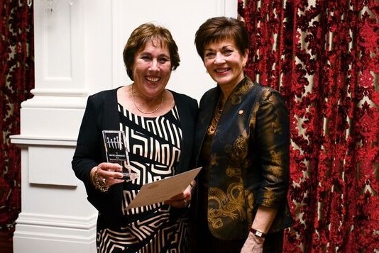 An image of Dame Patsy presenting an Award for Outstanding Service to Mrs Carol Calkoen
