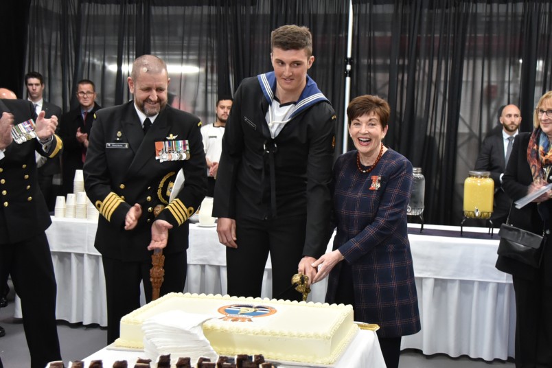 Image of Dame Patsy cutting the cake with the youngest sailor Able Marine Technician Samuel Marsh
