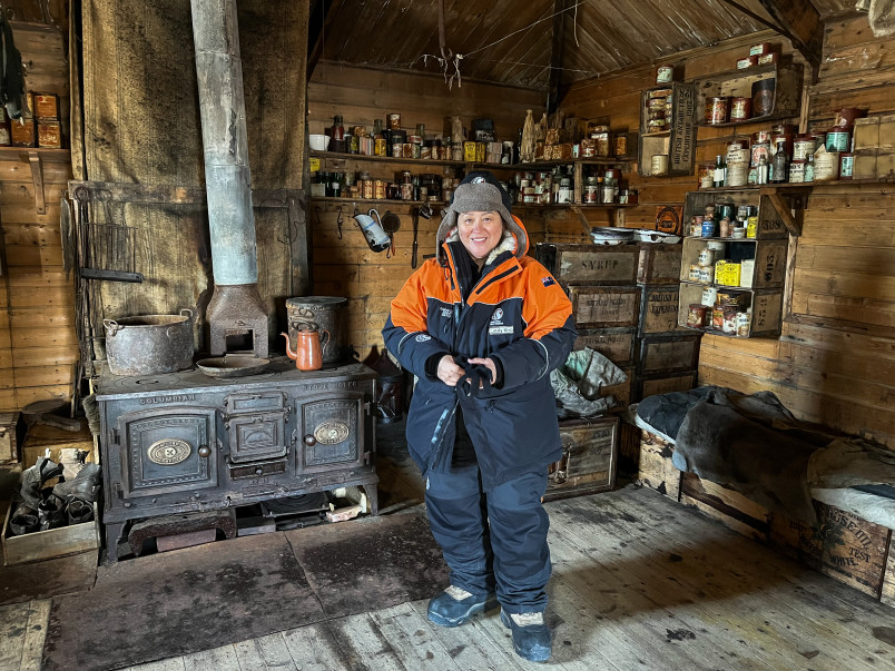 Dame Cindy inside Shackleton's Hut in front of a wrought-iron cooker.