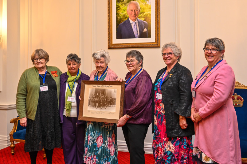 Rural Women NZ past and present presidents pose with a photograph of the original 1925 Women's Division of the Farmers' Union