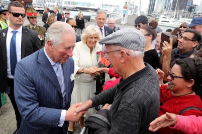 Prince Charles shakes a man's hand in a crowd of people