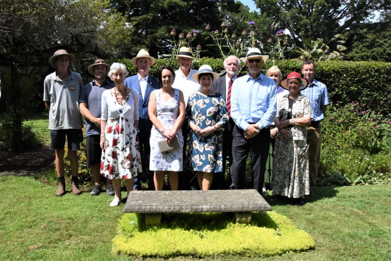 an image of Grounds Committee members and their guests joined Dame Patsy, Sir David and Government House gardeners in front of a bench dedicated to Sir Frank and Lady Mappin