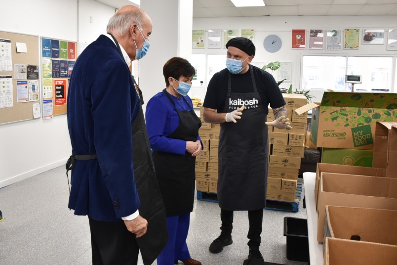 IMage of Volunteer Ziggy Ziya  teaching Dame Patsy and Sir David the finer points of food sorting