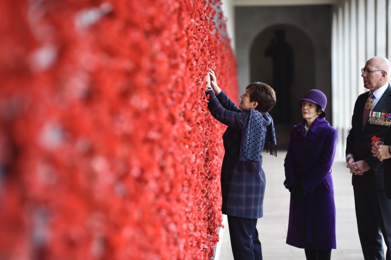 Image of Dame Patsy adding a poppy beside a name on the Roll of Honour