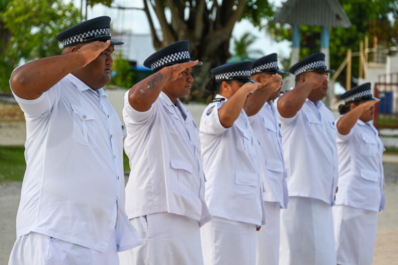 Local police officers salute during the flag-raising ceremony