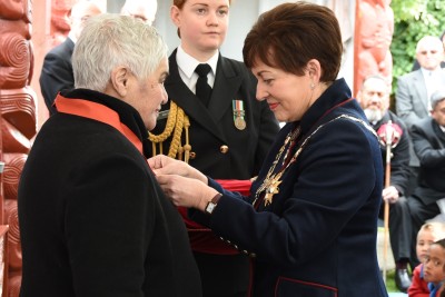 Image of Dame Patsy pinning on Dame Tariana's insignia