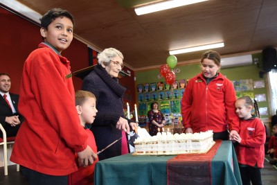 an image of Centenarian Mrs June Hall, an ex pupil, helps cut the school's birthday cake