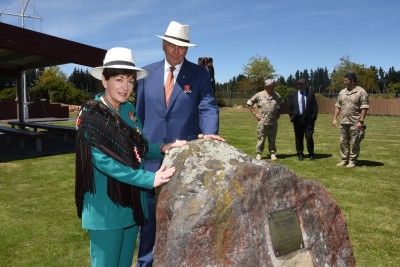 an image of Dame Patsy and Sir David touching a stone of remembrance on the marae