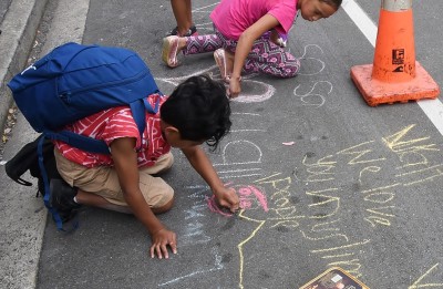 Image of children drawing messages of support on the footpath outside the mosque