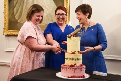 Image of Dame Patsy and Good Bitches Baking founders Nicole Murray and Marie Fitzpatrick cutting the cake