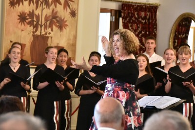 Image of NZSSC Music Director Sue Densem bringing in the audience for "Jingle Bells" 