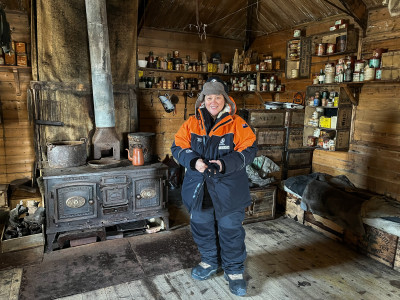 Dame Cindy inside Shackleton's Hut in front of a wrought-iron cooker.