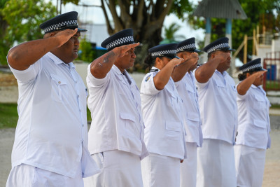 Local police officers salute during the flag-raising ceremony